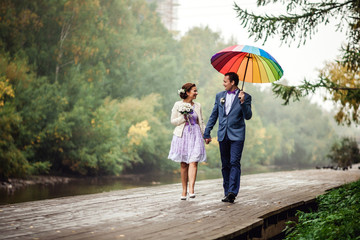 Happy Bride and groom at wedding walk with color umbrella. Autumn style  concept.