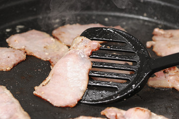 Bacon being fried in a pan