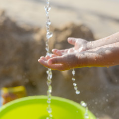 Closeup on child having fun with water on sea beach outdoors background