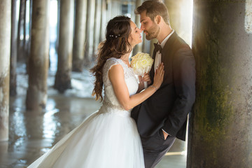 Romantic couple newlyweds embrace kiss by ocean beach pier attractive lovers