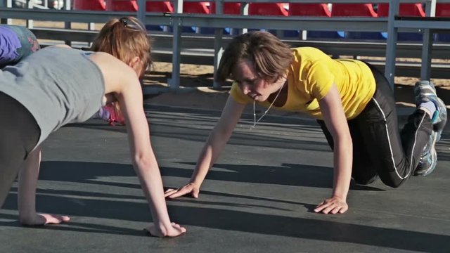 Two young women doing push-ups and clapping hands
