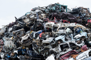 Dumping ground. Scrap metal heap. Compressed crushed cars is returned for recycling. Iron waste ground in the industrial area. Stacked automobile
