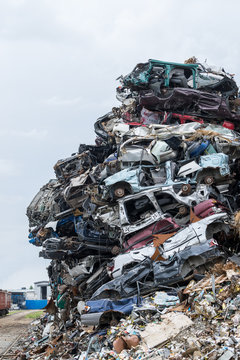 Dumping ground. Scrap metal heap. Compressed crushed cars is returned for recycling. Iron waste ground in the industrial area. Stacked automobile