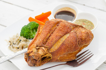 Fried pig leg with vegetables and sauce on plate