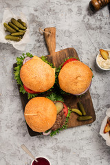 Three fresh homemade different hamburgers on wooden board