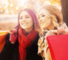 Couple of young women with shopping bags in the park