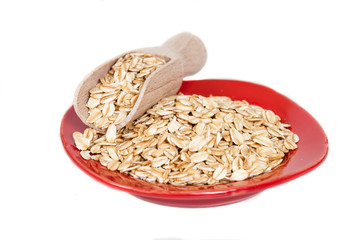 red dish  with oats flakes pile on white background.