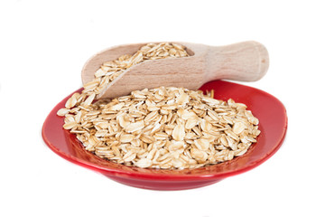 red dish  with oats flakes pile on white background.