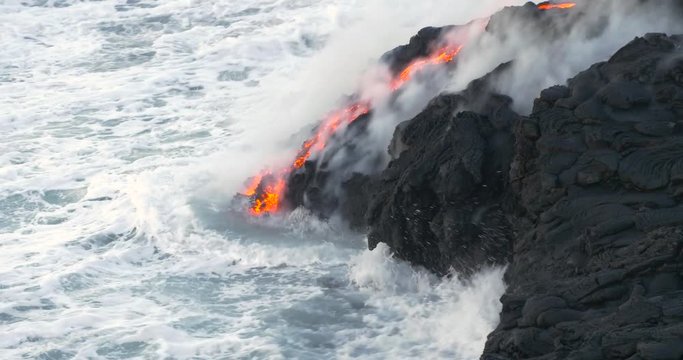 Volcanic Eruption Lava flowing into the water Hawaii. Steam rising from waves as molten lava flows into ocean waters Big Island Hawaii.