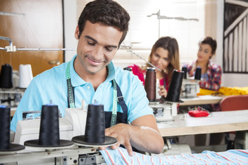 Fototapeta premium Male Tailor Stitching At Workbench In Sewing Factory