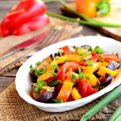 Stewed peppers with eggplant and garlic. Red and orange pepper stew with eggplant and garlic and topped with chopped green onions. Bright vegetable stew recipe. Closeup