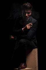 dramatic elegant young man in suit is smoking