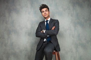 seated young businessman dreaming away with hands crossed