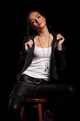 woman in leather clothes is pulling her collar and sits
