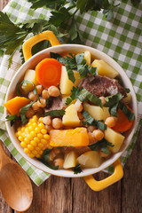 South American cuisine: thick soup Pouchero close-up in a pot. Vertical top view
