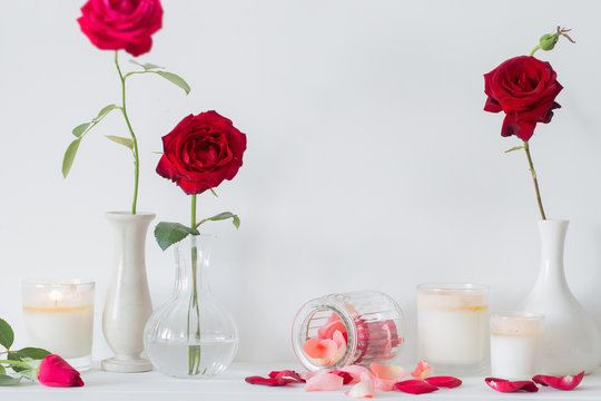 roses in a vase and candles on white background