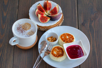 Cappuccino and cottage cheese pancakes with figs and jam for breakfast on  wooden background. Sweet figs.