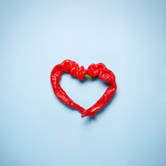 Top view of a farm sweet peppers in a heart shape on a blue background