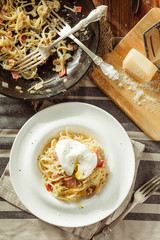 Overhead view of plate of spaghetti Carbonara with poached egg. Rustic styled