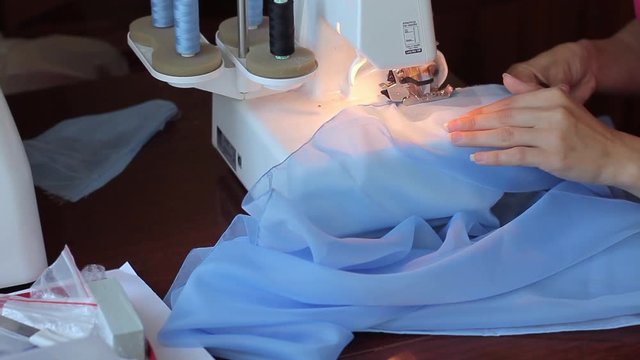 Woman treated tissue using overlock. Women's hands. Quickly sew close-up.