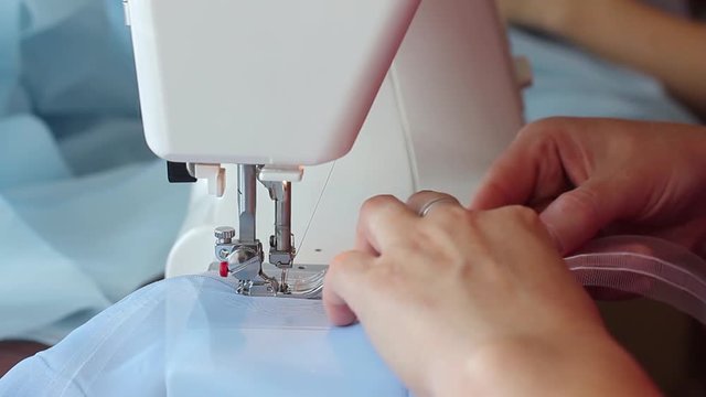 Woman sews on the sewing machine. Women's hands. Close-up.