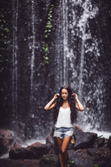 Fototapeta na wymiar Beautiful brunette woman enjoying near waterfall
