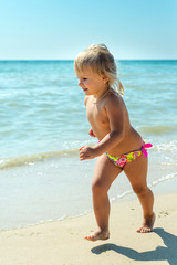 The child, a little girl running along the coast in the summer vacation.
