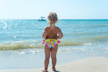 The child, a little girl playing on the beach.