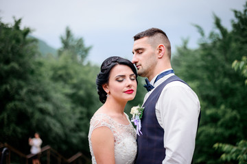 Beautiful stylish newlyweds posing outside
