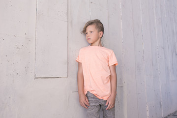 Stylish boy leaned on the wall and looking to the side . 