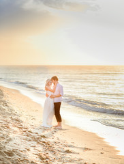 Fototapeta na wymiar Beautiful stylish couple posing in sunlight on the beach