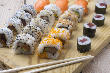 Different Sushi rolls,wasabi and ginger on a plate on wooden bac
