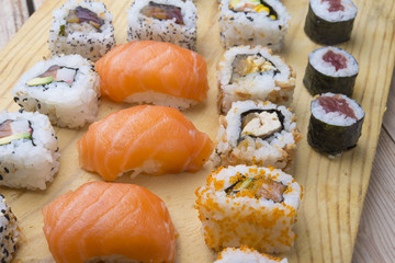 Different Sushi rolls,wasabi and ginger on a plate on wooden bac