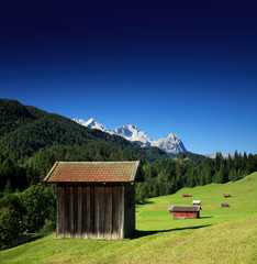 Fototapeta na wymiar Bergwiese in den Bayerischen Alpen, Typische Almhütten, hinten die Zugspitze, bei Mittenwald, Bayern, Deutschland