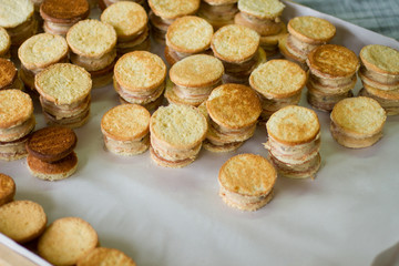 Lots of cookie sandwiches. Yellow biscuits with custard. Fresh and tasty sweets. Dessert cooked in oven.