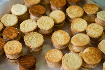 Sandwich cookies of yellow color. Lots of biscuits with custard. Simple dessert cooked at home. Pastry with vanilla filling.