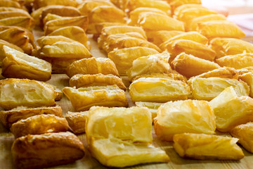 Puffs on wooden board. Yellow pastry under sunlight. Early morning at the bakery. Product made of dough.