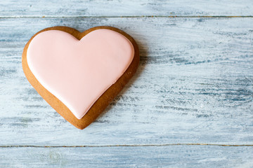 Cookie in shape of heart. Brown biscuit with pink glaze. Small romantic dessert. Symbol of love.