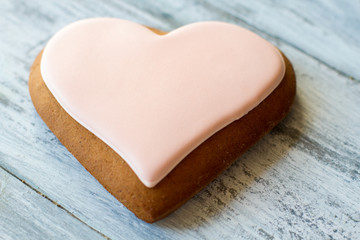 Obraz na płótnie Canvas Biscuit shaped as heart. Cookie with light pink glaze. Make surprise for loved one. Recipe for love.