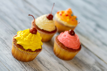 Cupcakes on gray background. Yellow cream and cherry. For lovers of sweet treats. Dessert with vanilla taste.