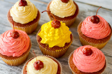 Cupcakes with bright icing. Small baked desserts. Dough and buttercream. Yummy treats for guests.