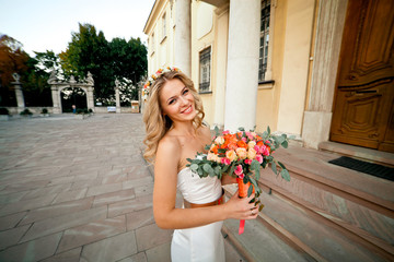 Fototapeta premium Beautiful happy bride is posing with her bouquet