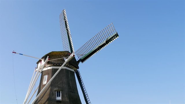 Rotating the head with wings on top of old historic windmill
