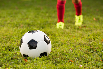 Aspiring young kid is seen training soccer / football on a local football field.