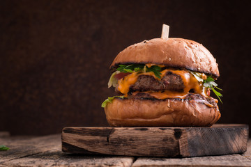 Tasty grilled burger with lettuce and mayonnaise ,on a rustic wooden table