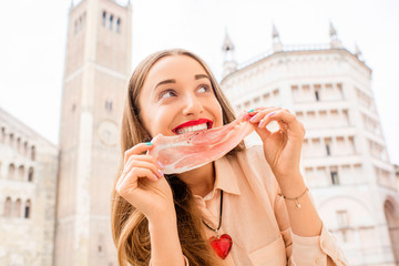 Young woman with prosciutto on the main square in Parma town in Italy. Parma is a city in the north...