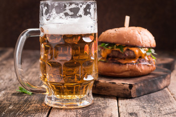 Fresh and tasty hamburger with a beer on a wooden table.