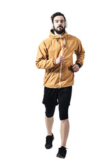 Determined young jogger  in jacket with headphones running towards camera. Toned desaturated full body length portrait isolated on white studio background.