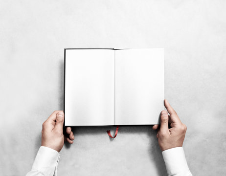 Hand Holding Blank Opened Book Mock Up With White Pages. Person Reading Empty Paperback Mockup. Black Notebook Inside Template. Publication Design Leafing Man. Textbook Spread With Bookmark.