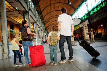 Father, mother and two children stand in a waiting room at the station.